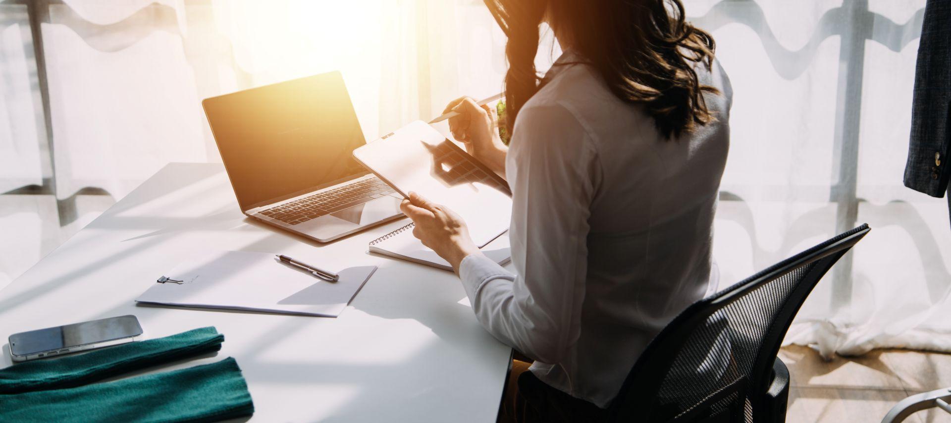 Woman working with laptop and tablet in a home office